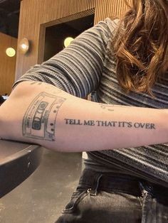 a woman with a tattoo on her arm saying tell me that it's over