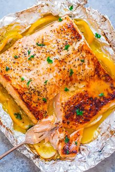 a piece of salmon on foil with lemon sauce and parsley garnishes