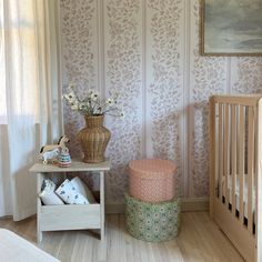 a baby's room with a crib, dresser and wallpaper