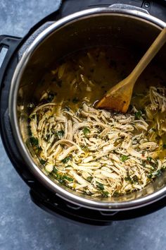 a pot filled with noodles and vegetables being stirred by a wooden spoon