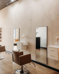 A salon space with two dark beige shampoo systems with black wash bowls and matching styling chairs standing in front of white wall-mounted styling stations with gold hardware and large mirrors. Salon Station Ideas, Beauty Salon Stations, Nail Salon Equipment, Minerva Beauty, Salon Design Ideas, Manicure Tables, Home Hair Salons, Beauty Salon Furniture, Hair Salon Design