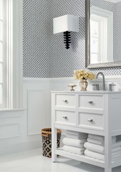 a white bathroom with black and white wallpaper, a vanity sink and mirror in the corner