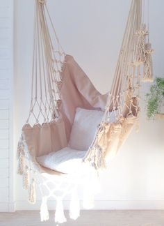 a hammock hanging from the ceiling in a room with white walls and wood floors