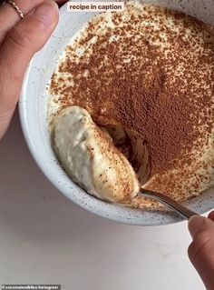 a person is spooning in a bowl with cinnamon and powdered sugar on top