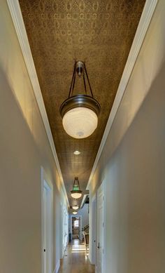 a long hallway with light fixtures and wood flooring on either side of the room