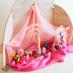 a pink cloth with some toys on it and a candle in the middle next to it