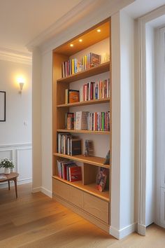 a book shelf with many books on it in a living room next to a window