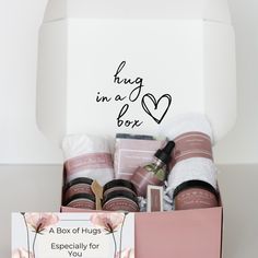 a pink gift box filled with personal care items and a white card that says sending you hugs