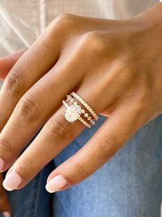 a woman's hand with three different rings on her fingers and one ring in the middle