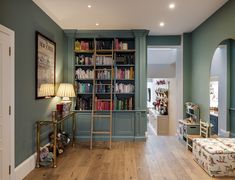 a living room filled with furniture and bookshelves next to a doorway that leads to a hallway