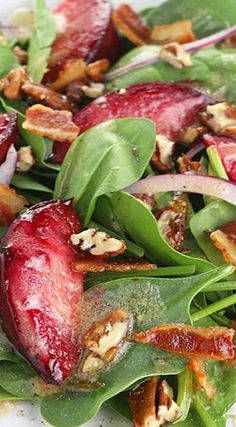 a salad with spinach, apples and walnuts on it is ready to be eaten