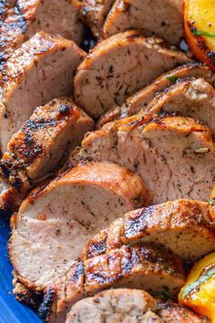 meat and vegetables on a blue plate with lemons, tomatoes and peppers in the background