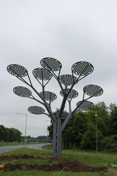 a large metal tree sitting on the side of a road