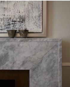 a marble fireplace mantel with two silver vases sitting on it's mantle