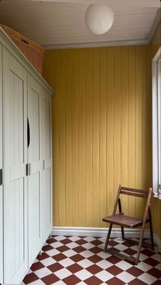 a chair sitting in the corner of a room with yellow painted walls and checkered floor