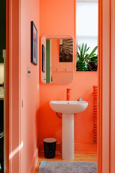 an orange bathroom with a sink and mirror