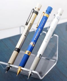 three pens are sitting in a clear holder