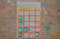 an orange and white bag with buttons on it sitting on a wooden table next to paint splatters