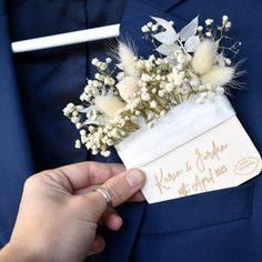 a man in a blue suit holding a bouquet of flowers with writing on the label