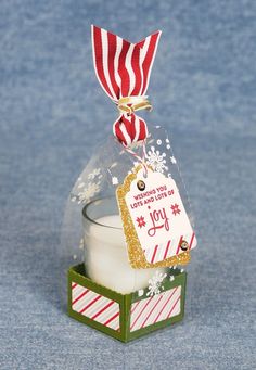 a candle with a tag on it sitting in a glass container filled with snowflakes