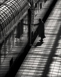 black and white photograph of a person standing at a train station