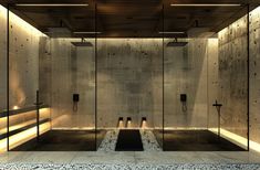 an empty bathroom with stone flooring and glass partitions on the wall, surrounded by pebbles