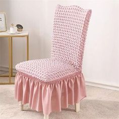 a pink chair with a ruffled skirt on the bottom and back, sitting in a white room