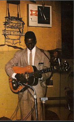 a man in a suit playing an electric guitar