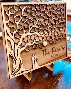 the laser cut wedding card holder is made out of wood and has a tree with hearts on it