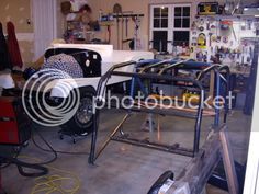 a man working on an assembly line in a garage with tools and other items around him