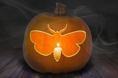 a pumpkin with a lit candle in the shape of a butterfly