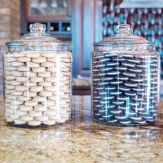 two glass jars filled with cookies sitting on top of a counter