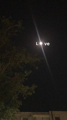 the words lve are lit up in the night sky above a building with trees