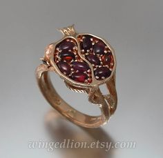 "For ages, pomegranates have symbolized love, fertility, and abundance. Inspired by the ancient myth of Persephone, the queen of the underworld and the goddess of spring growth, we designed this beautiful ring. The ring will be made to order in the size specified by the customer. The Pomegranate ring will be made in 14k rose gold. The ring's top is shaped as a half of ripe pomegranate and set with 10 natural red garnet oval cabochons (3x5 mm each). The shank is designed to look like the pomegran Cottagecore Wedding Ring, The Goddess Of Spring, Apple Jewelry, Goddess Of Spring, Winged Lion, Grape Apple, Pomegranate Jewelry, Cute Engagement Rings, The Underworld