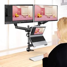 a woman sitting at a desk with two computer monitors on it and the screen is turned on