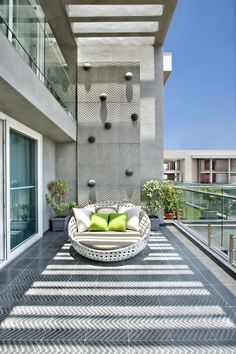 a white couch sitting on top of a wooden floor next to a window covered balcony