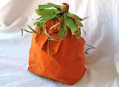 an orange bag with green leaves on it sitting on a white cloth covered tablecloth