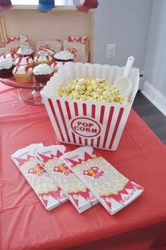 a red table topped with cupcakes and popcorn