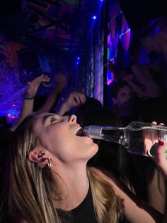 a woman drinking from a bottle at a party