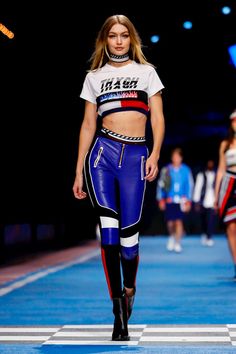 a model walks down the runway wearing blue leather pants and a cropped t - shirt