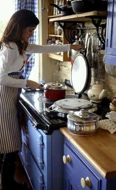 a woman standing in front of a stove preparing food on top of a wooden counter