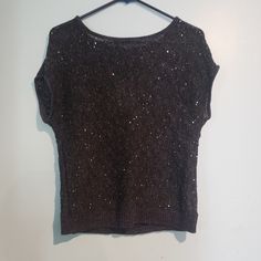 a black crop top hanging on a white wall next to a wooden hanger with an object in it