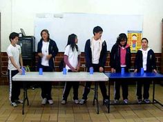 a group of young people standing next to each other in front of a blue table