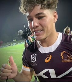 a young man is giving the thumbs up sign at a football game with his cameraman