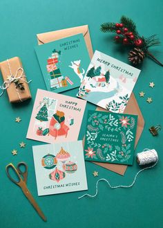 four christmas cards on top of a table next to some scissors and other holiday decorations