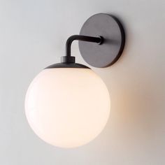 a light that is on the wall next to a white wall mounted lamp with a black arm