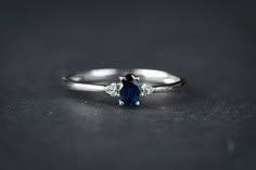 a white gold ring with an oval blue sapphire and three small diamonds on the side