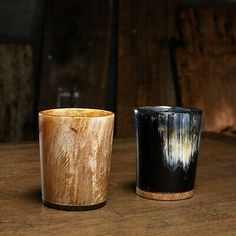 two black and white cups sitting on top of a wooden table next to each other