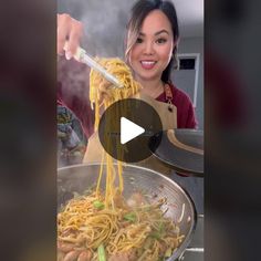 a woman is stirring noodles in a wok