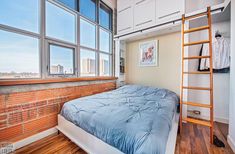 a bed sitting under a window next to a wooden ladder